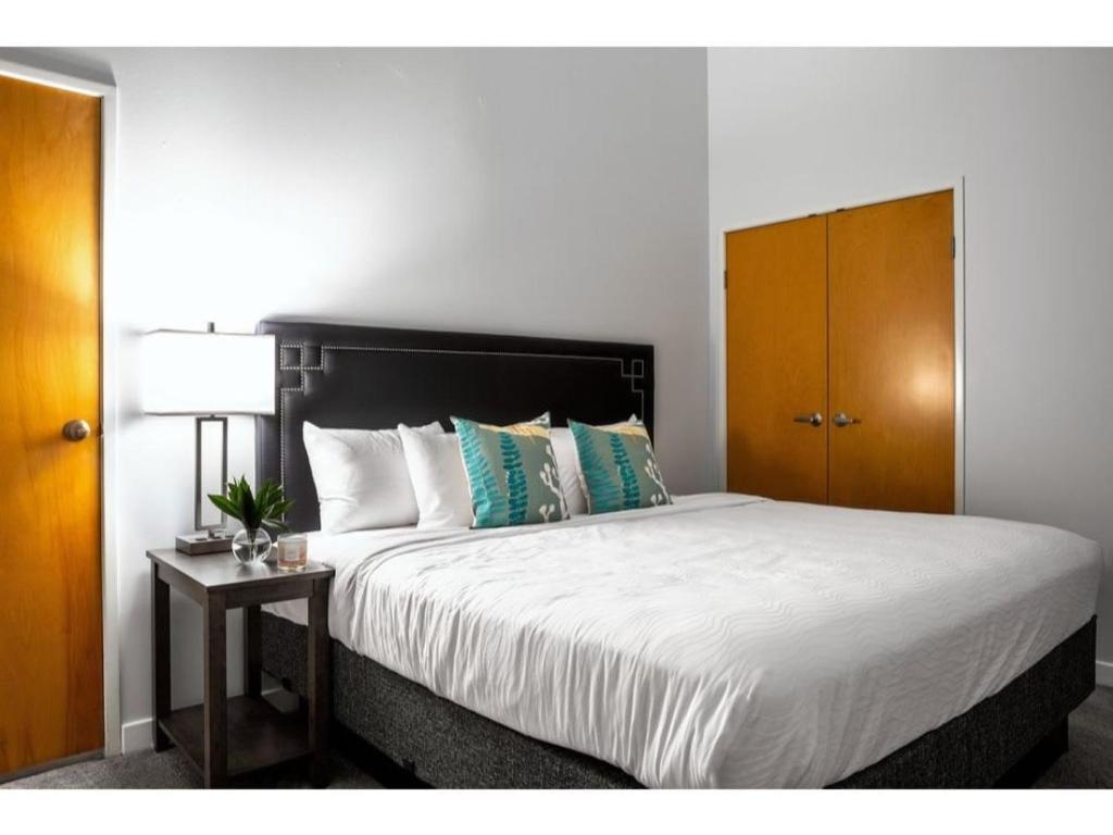 a bedroom with a large bed and a wooden cabinet at Modern Apartment Close To Everything CozySuites in Indianapolis