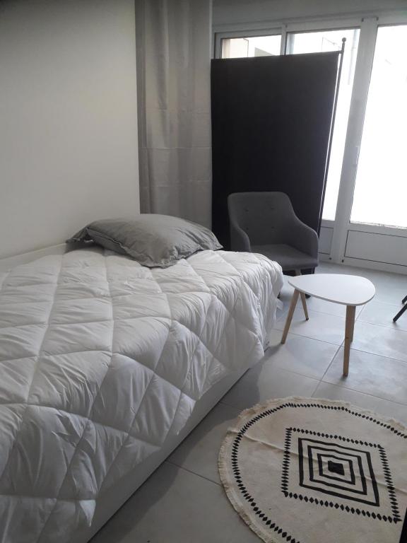 a bedroom with a bed and a chair and a table at Studio moderne bords de Loire in Juigné-sur-Loire