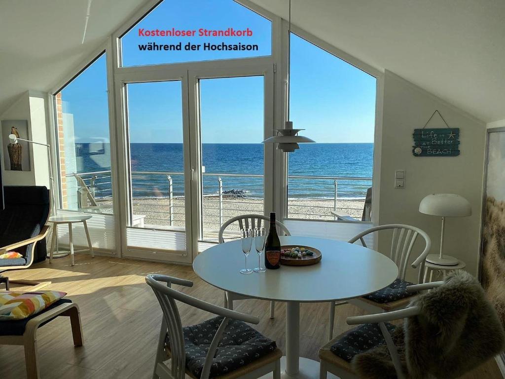 - une salle à manger avec une table et une vue sur l'océan dans l'établissement Meeresblick-Strandkorb-Haus-3-WE-46, à Hohwacht