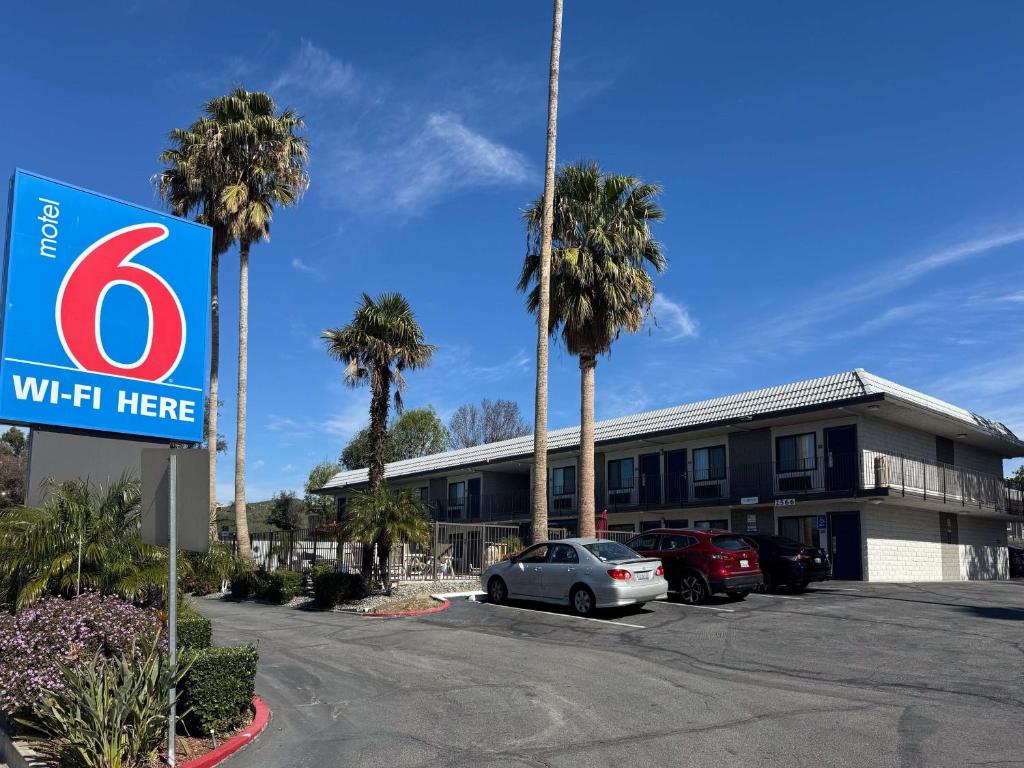 a sign in front of a building with palm trees at Motel 6-Simi Valley, CA in Simi Valley