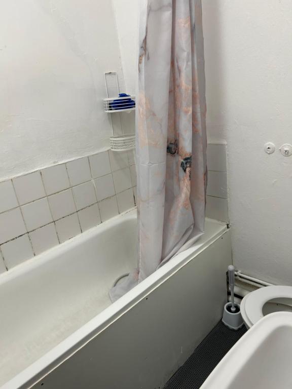 een badkamer met een douchegordijn naast een toilet bij House with private garden in Londen