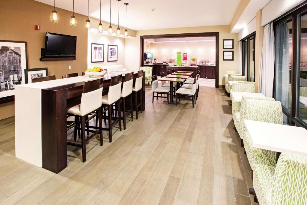 un restaurante con un bar con mesas y sillas en Hampton Inn Elizabethtown, en Elizabethtown