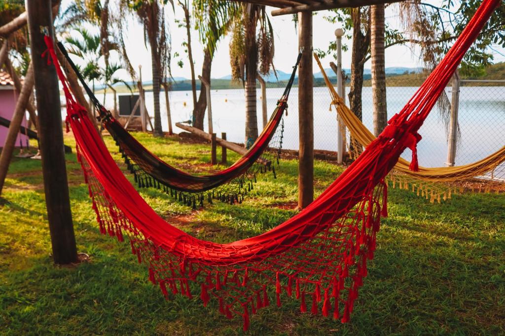 a red hammock on the grass near a body of water at Pousada Estância Mineira in Guapé