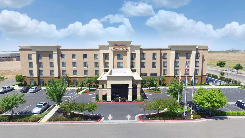 un gran edificio con un estacionamiento delante de él en Hampton Inn & Suites Madera, en Madera