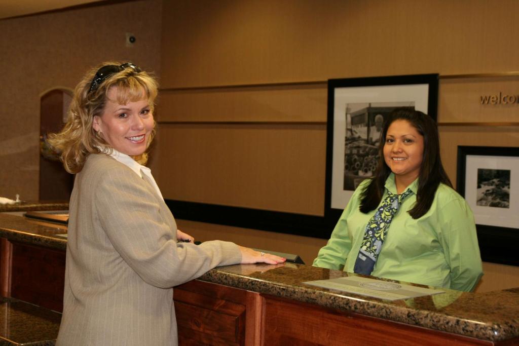 two women are standing at a reception desk at Hampton Inn & Suites Farmington in Farmington