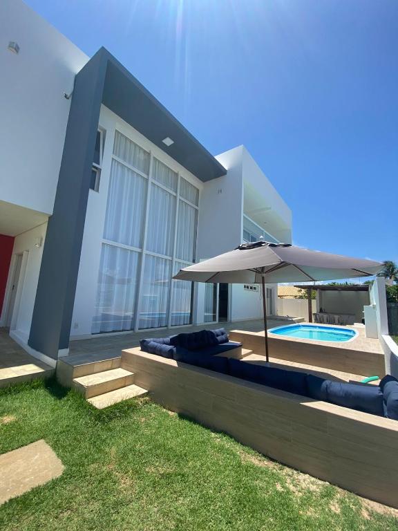a house with an umbrella and a swimming pool at Refúgio da Praia Aracaju in Aracaju