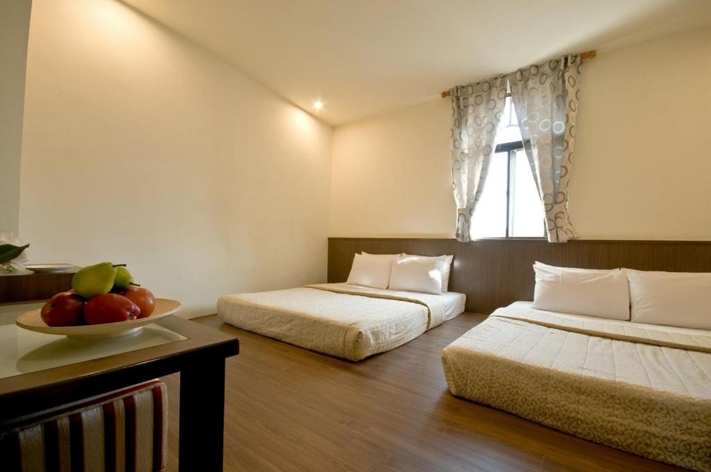 una camera con due letti e un cesto di frutta su un tavolo di Good Ground Hotel Tainan a Tainan
