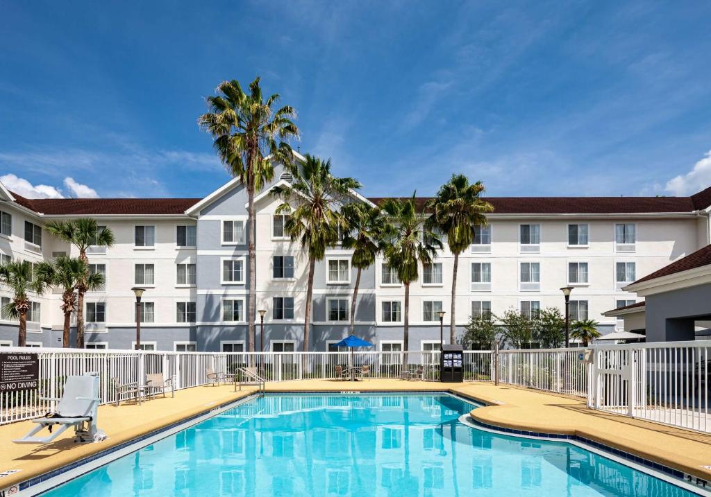 a pool in front of a hotel with palm trees at Homewood Suites by Hilton Gainesville in Gainesville