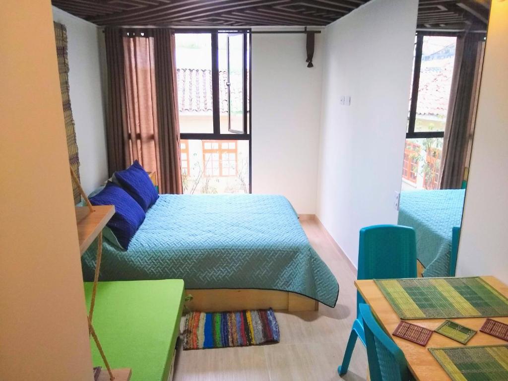 Un dormitorio con una cama y una mesa y ventanas. en Downtown, Blue Green Home, Nature inspired, en Bogotá