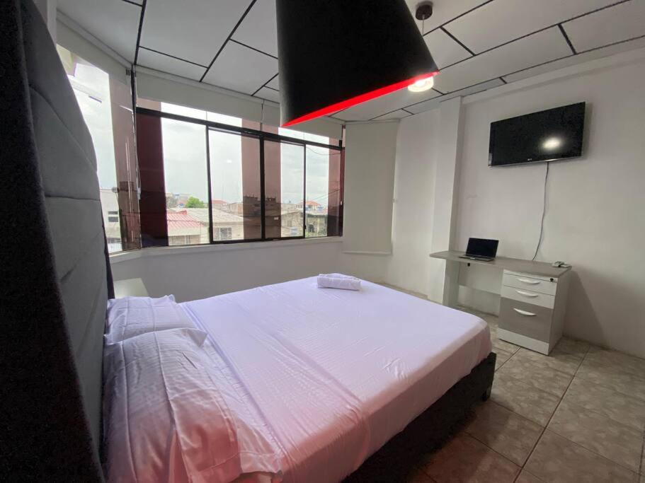 a bedroom with a bed and a television in it at Moderno, grande, amplia vista, parqueo in Machala