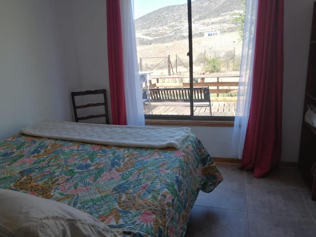a bedroom with a bed and a window with a view at La Serena Cabaña de campo entre cactus y colibríes in La Serena