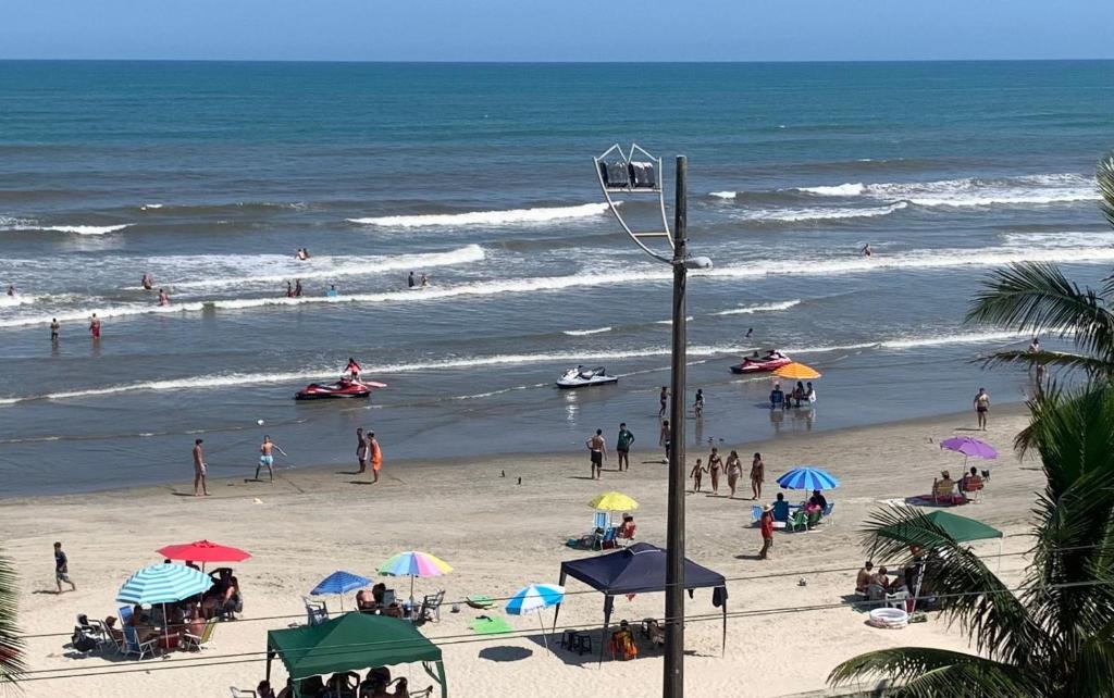 a group of people on a beach with umbrellas at Belíssimo apartamento frente mar in Mongaguá