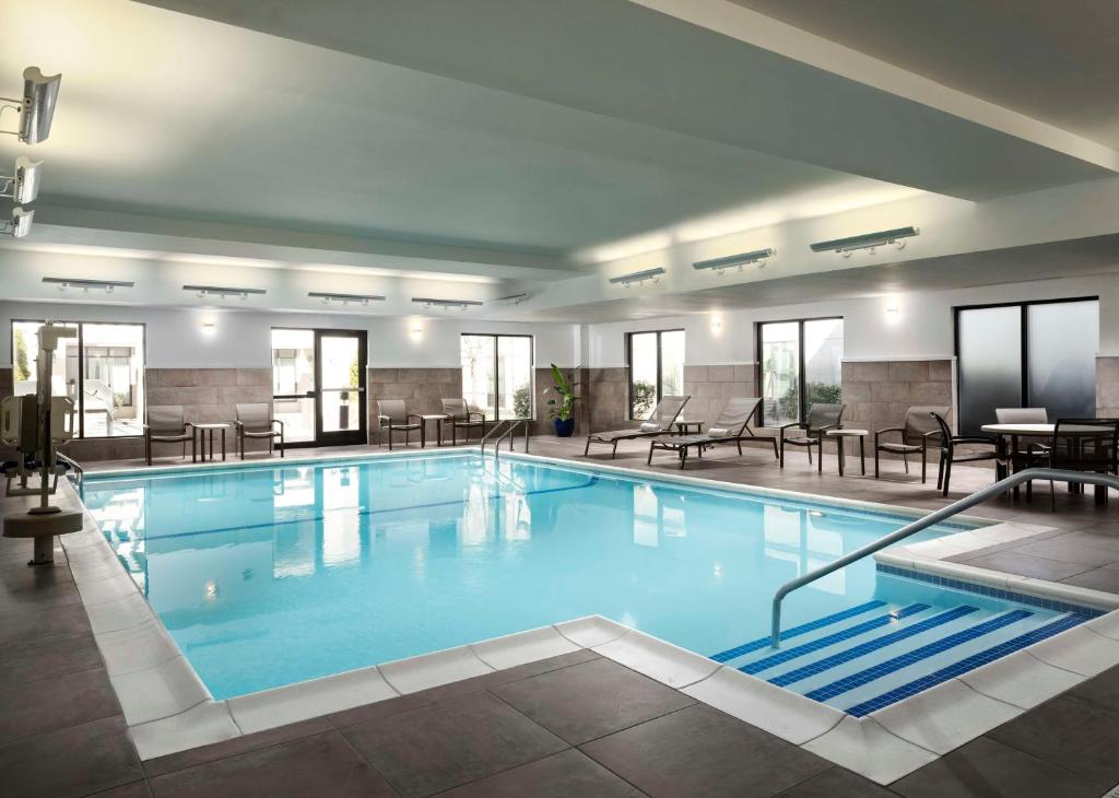 ein großer Pool in einem Hotel mit Tischen und Stühlen in der Unterkunft Homewood Suites by Hilton Carle Place - Garden City, NY in Carle Place