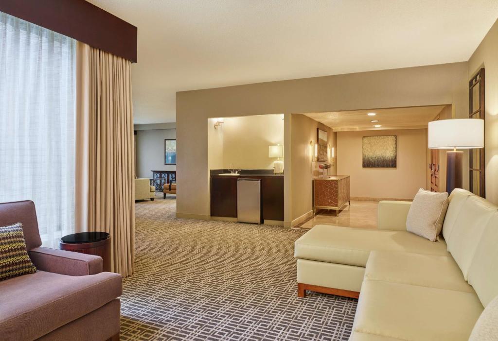 a living room with a white couch and a living room with a kitchen at DoubleTree by Hilton Houston Intercontinental Airport in Houston