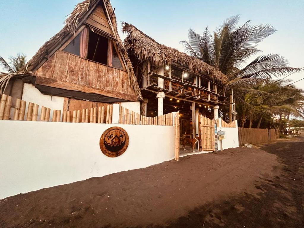 uma casa com um telhado de palha numa parede em Mi Casa en la Playa em Escuintla