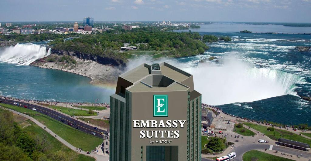 a building with an embassy suites sign in front of a waterfall at Embassy Suites by Hilton Niagara Falls/ Fallsview in Niagara Falls