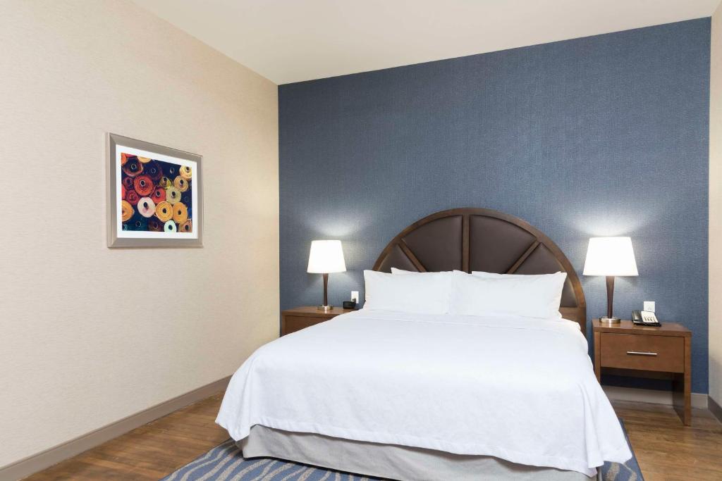 a bedroom with a large white bed and a blue wall at Homewood Suites by Hilton Grand Rapids Downtown in Grand Rapids