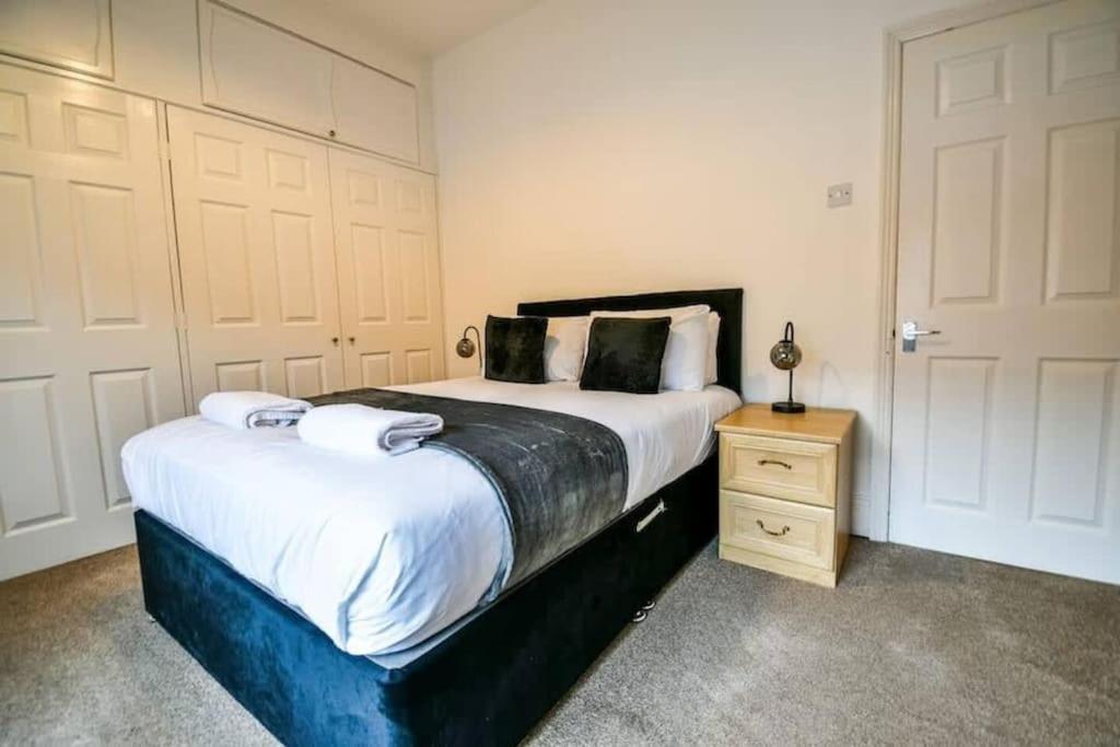 a bedroom with a large bed and a wooden night stand at Fitzwilliam House -3 Bed House in Redcar