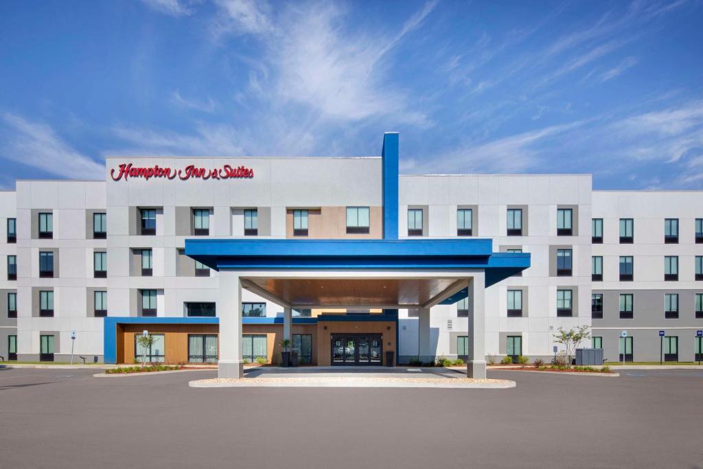 a large white building with a red sign on it at Hampton Inn & Suites D'Iberville Biloxi in Biloxi