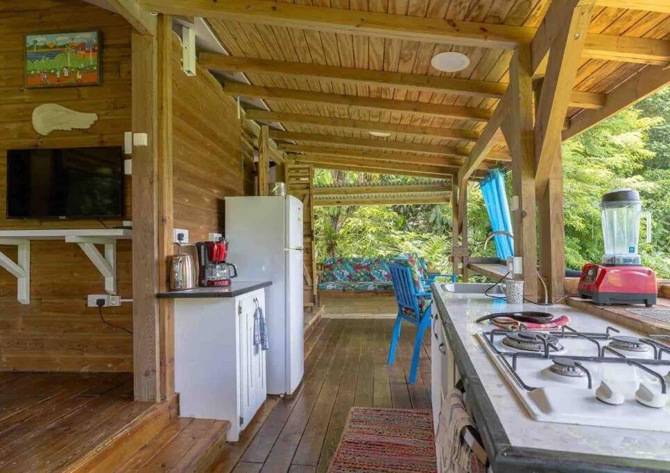 a kitchen with a stove in a cabin with a porch at Sizo Treehouse Cottage in Roseau