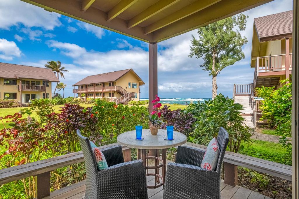 Hanalei Colony Resort E1 في هانالي: طاولة وكراسي على شرفة مطلة على المحيط