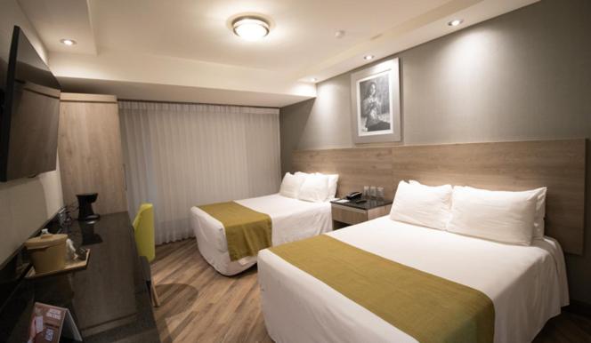 a hotel room with two beds and a television at Hotel Araiza Hermosillo in Hermosillo
