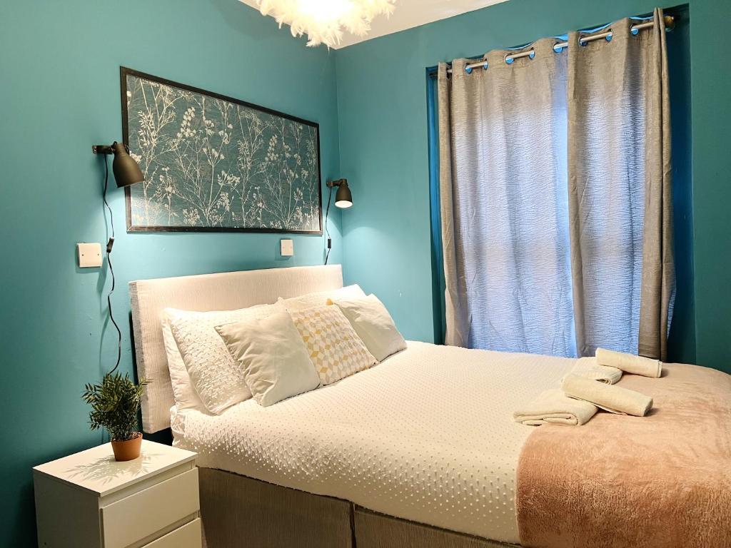 - une chambre avec un lit aux murs bleus et une fenêtre dans l'établissement Dublin Central Apartment, à Dublin