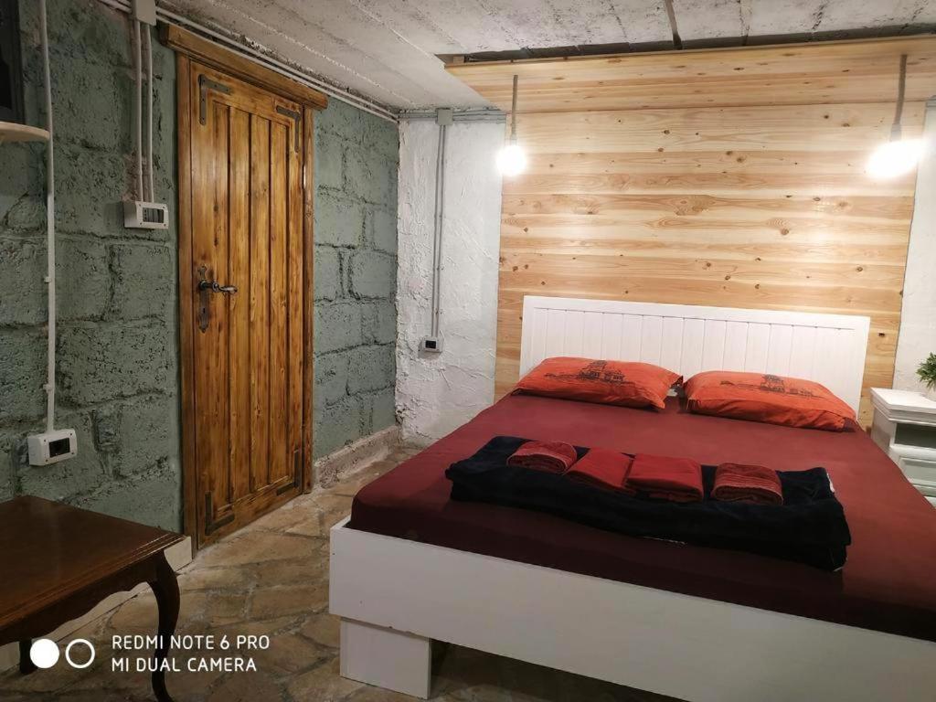 sypialnia z łóżkiem z drewnianą ścianą w obiekcie Villa Old Town w mieście Podgorica