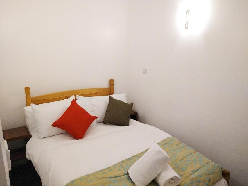 sypialnia z białym łóżkiem z czerwonymi i zielonymi poduszkami w obiekcie Park Lane Ground Floor Apartment - Workington Town Centre w mieście Workington