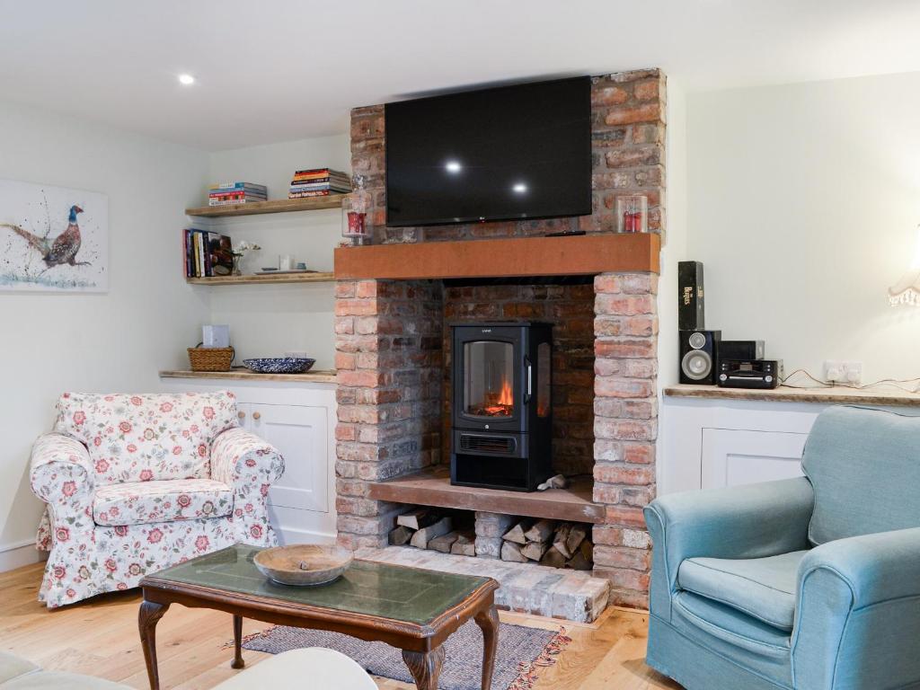 a living room with a brick fireplace with a tv at The Old Hemmel-uk44853 in Holton