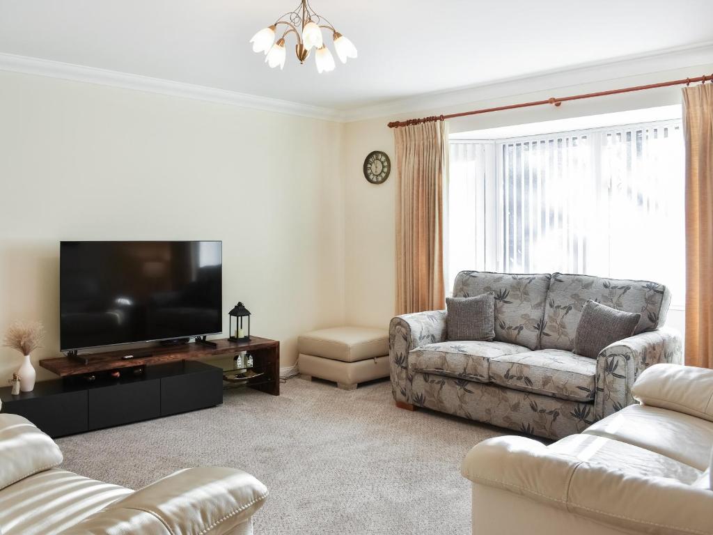 sala de estar con sofá y TV de pantalla plana en Rycon en Turriff