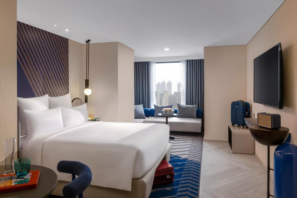 ein Hotelzimmer mit einem großen Bett und einem Wohnzimmer in der Unterkunft TRIBE Living Bangkok Sukhumvit 39 in Bangkok