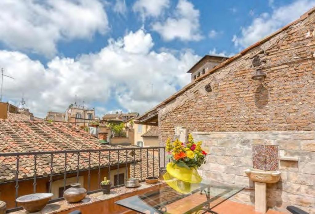 ローマにあるNavona Luxury Terrace Apartment - 12 guestsのレンガ造りの建物で、ガラステーブル付きのバルコニーが備わります。