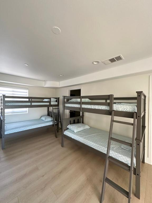 a room with three bunk beds and a wooden floor at Qazaq Hostel in Los Angeles