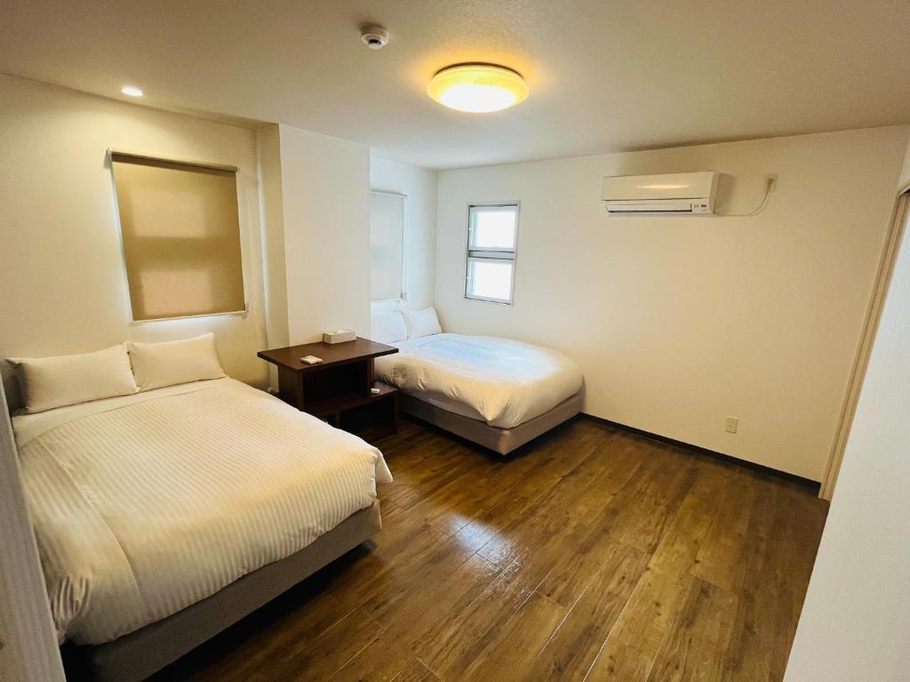 Una habitación de hotel con dos camas y una mesita de noche. en Mr,KINJO in RYCOM Kitanakagusuku - Vacation STAY 59274v, en Shimabuku