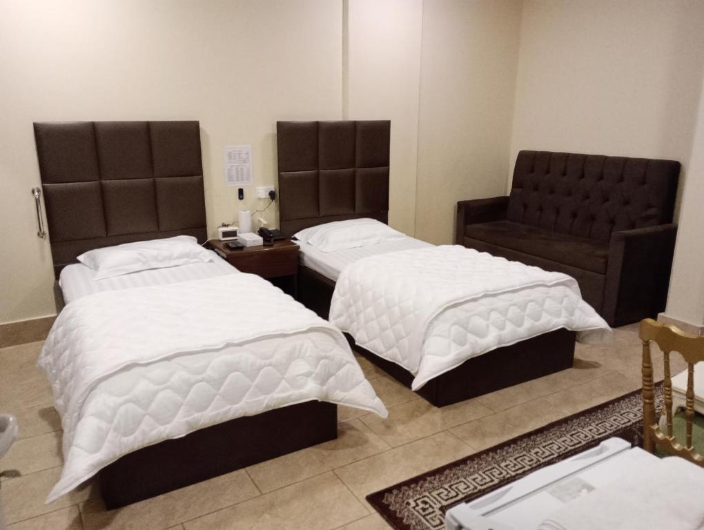 1 Schlafzimmer mit 2 Betten und einem Stuhl in der Unterkunft السرايا الاولى للشقق المخدومة in Al Hofuf
