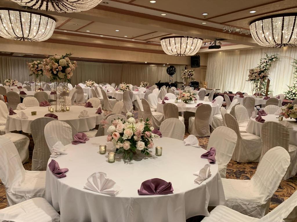 a banquet hall with white tables and chairs and flowers at Oxford Palace Hotel in Los Angeles