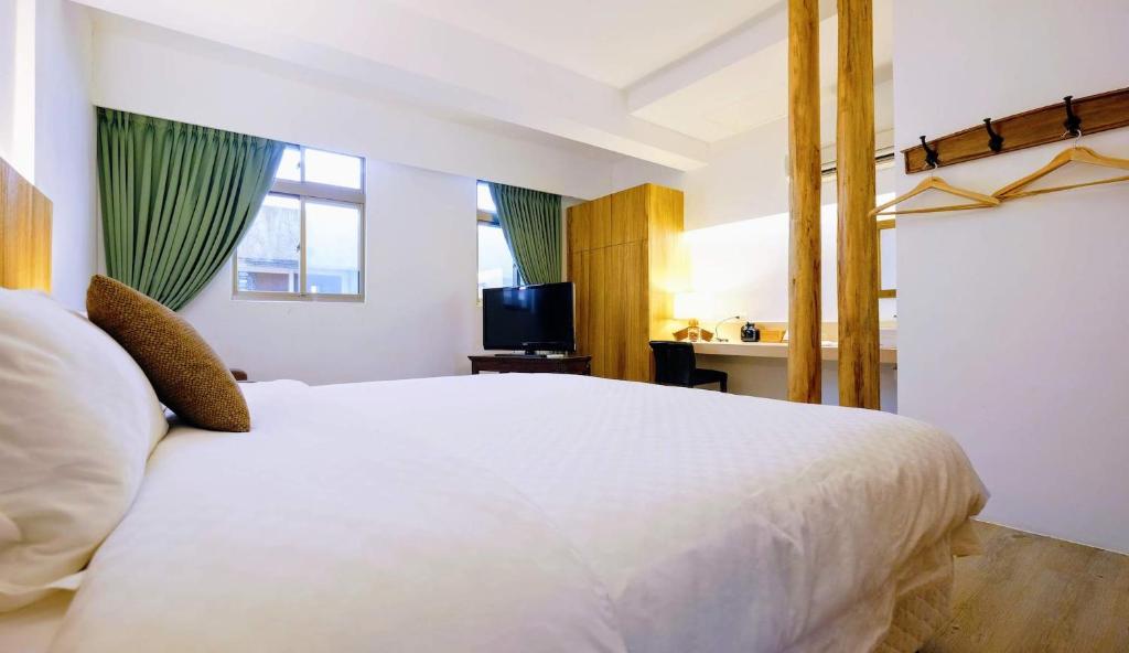 a bedroom with a large white bed and a desk at Shire Homestay in Luodong