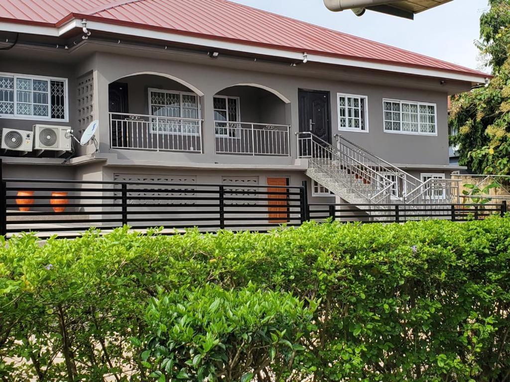 una casa con techo rojo y porche en Casa Consuelo Guest House, en Takoradi