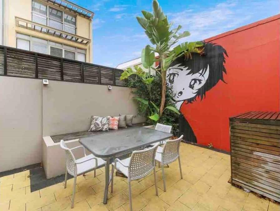 a patio with a table and chairs and a mural at Cosy Cottage Funky ICC Darling Harbour Sydney in Sydney
