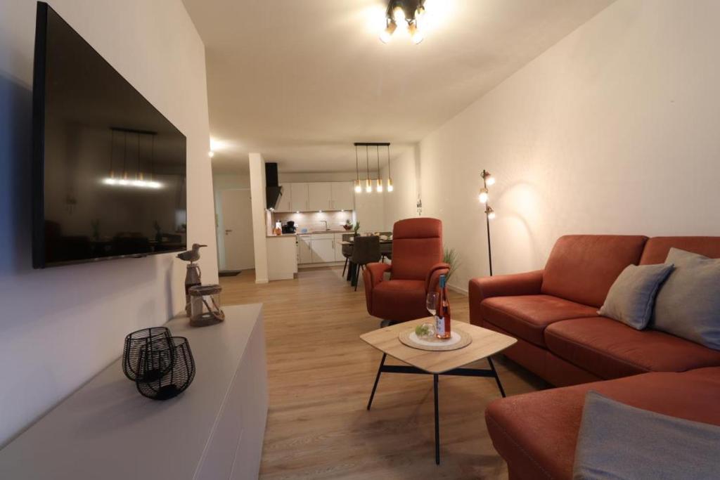 een woonkamer met een bank en een tafel bij Dorumer Sielhuus 7 - Ferienwohnung mit Terrasse und Sauna in Dorum