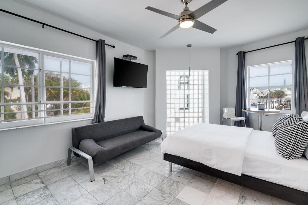 1 dormitorio con cama, sofá y ventanas en Best Location SOBE Top Floor 2 min to beach & fun, en Miami Beach