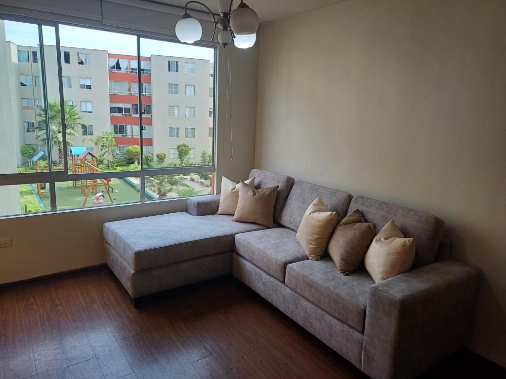 uma sala de estar com um sofá e uma grande janela em Habitación acogedora Orué em Lima