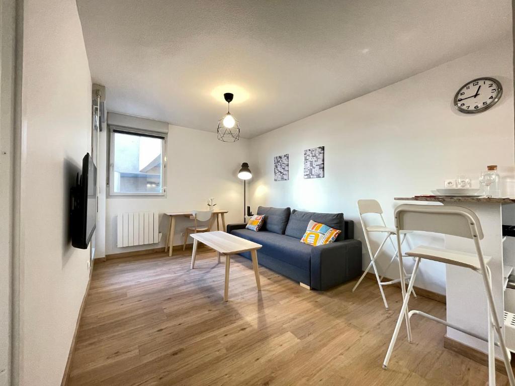 un salon avec un canapé bleu et une table dans l'établissement Airbus by Yumē, à Toulouse