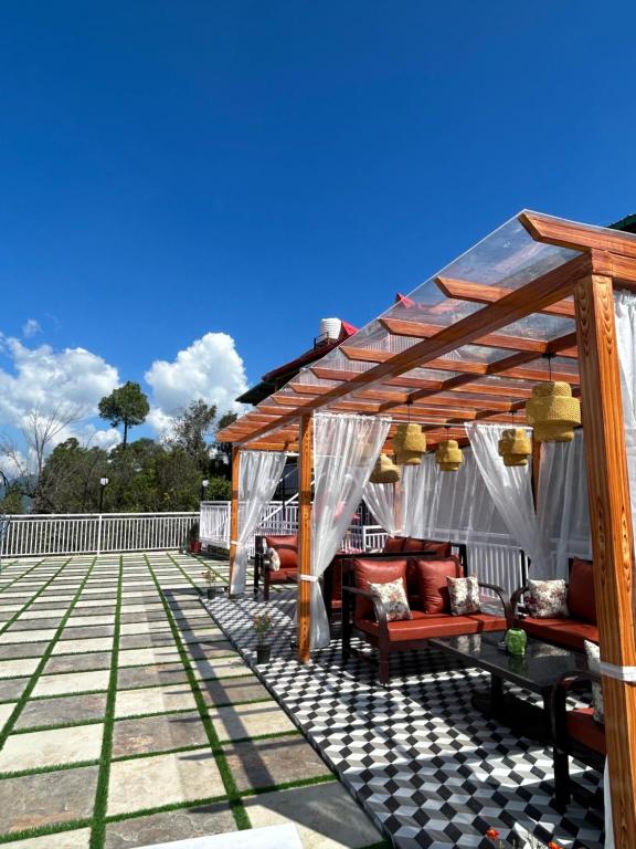 eine Pergola auf einer Terrasse mit Sofas und Stühlen in der Unterkunft Kasar Himalaya Holiday Home, Binsar Rd in Almora