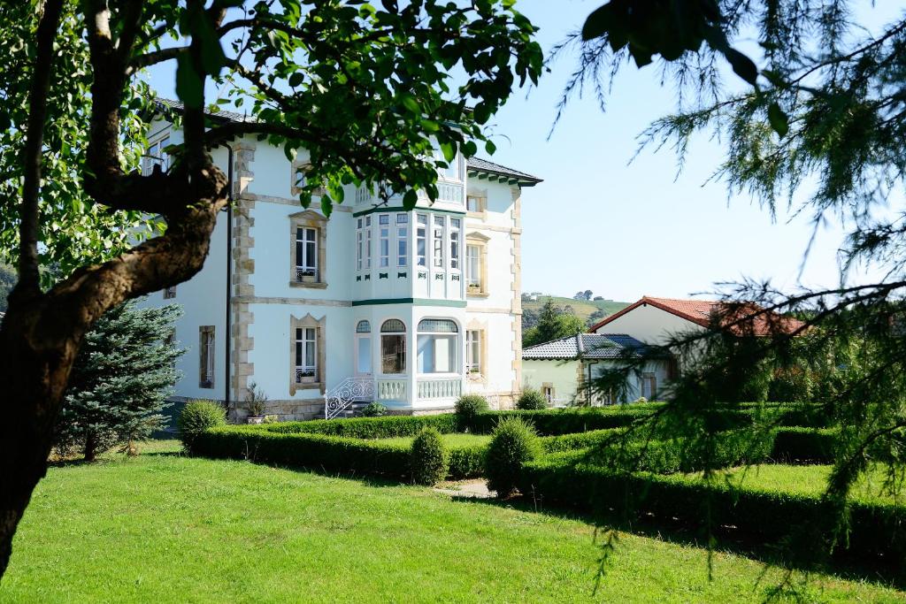 una grande casa bianca con un cortile verde di Hotel Rural El Solar del Mazo a Rada