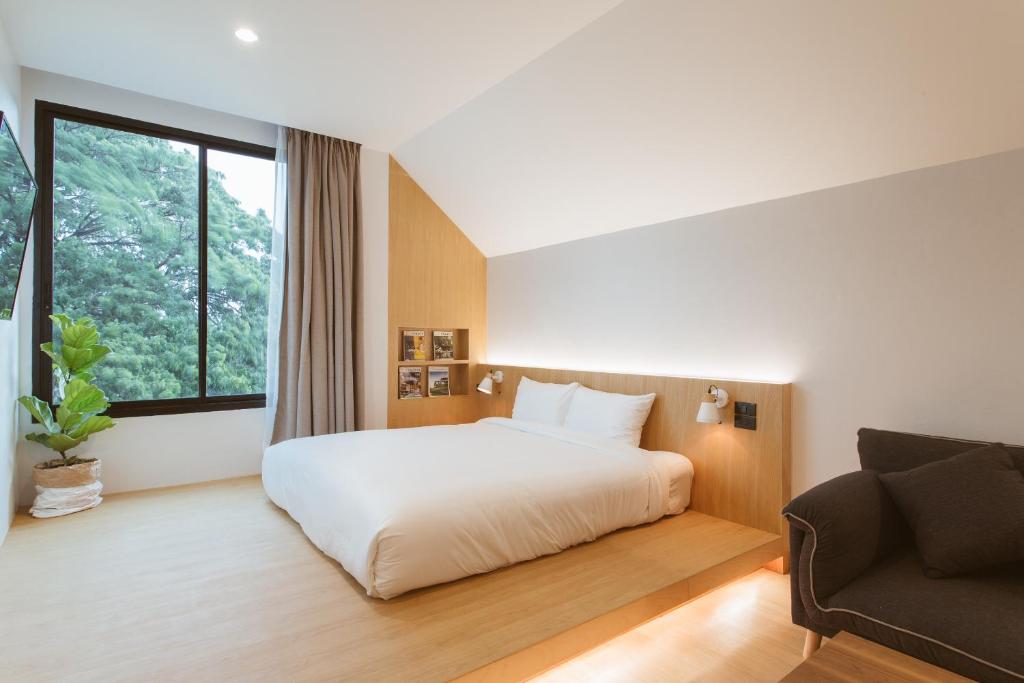 a bedroom with a white bed and a couch at Karpenter Lampang in Lampang