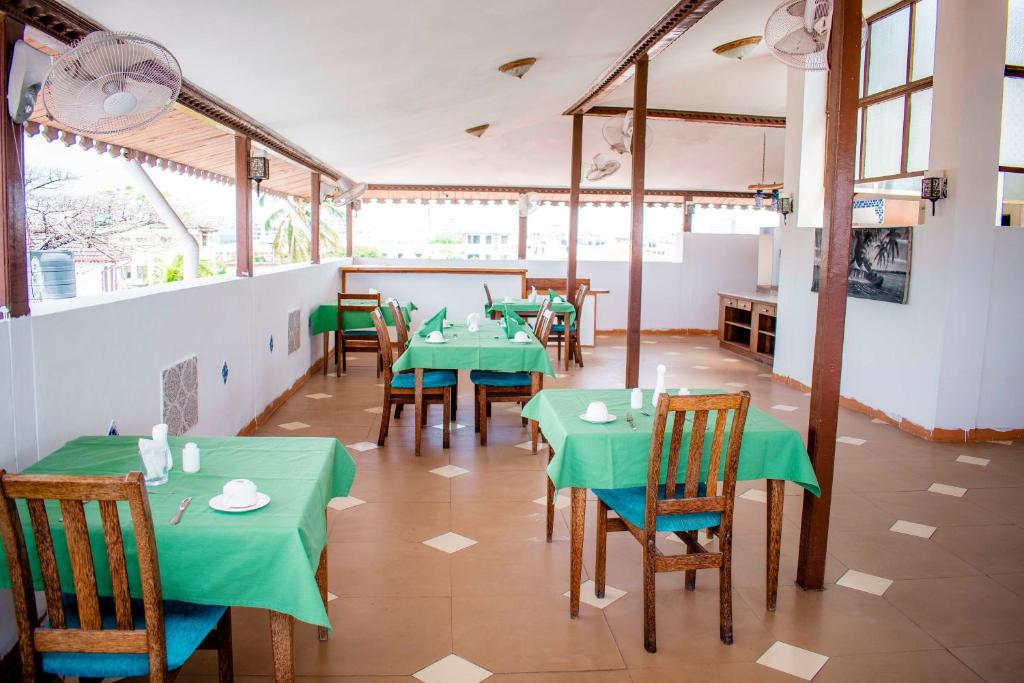 a restaurant with green tables and chairs in a room at The Island Stone Town hotel in Ngambo