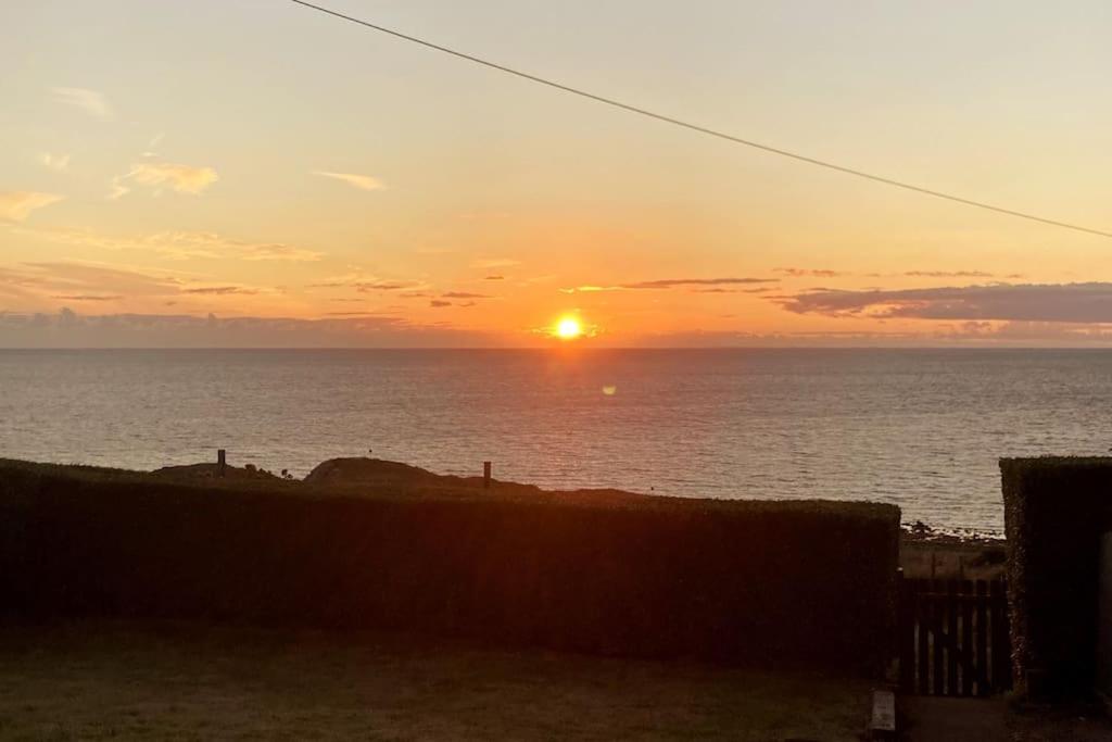a sunset over the ocean with the sun at ERIN NEAMH - Magnificent sea views cosy cottage in Cumbria 