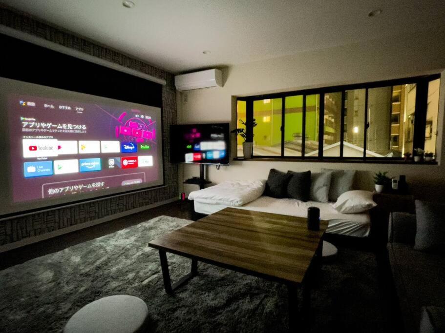 a living room with a couch and a large screen at TasoneStayOsaka なんば大国大山302 in Osaka